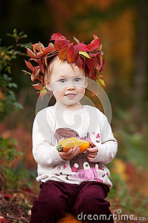 Cute little girl playing with vegetable marrow in autumn park. Autumn activities for children. Halloween and Thanksgiving time Stock Photo