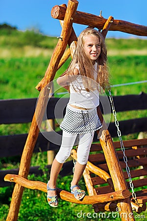 Cute little girl playing on wooden chain swing Stock Photo