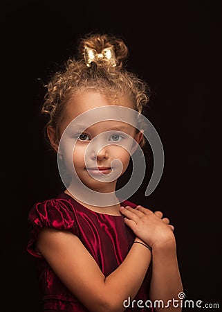 Cute little girl poses for the camera on a black background in the studio Stock Photo