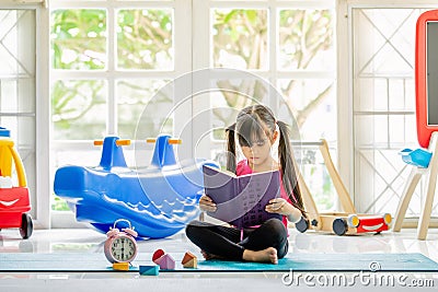 Cute little girl is reading a book . Funny kid having fun in kid Stock Photo