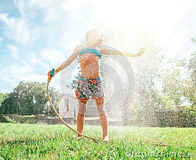 Cute little girl refresh herself from garden watering hose Stock Photo