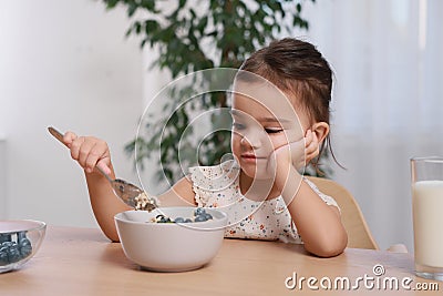 Cute little girl refusing to eat her breakfast at home Stock Photo
