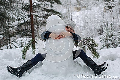 Cute little girl sculpts snowman in winter snowy Park Stock Photo