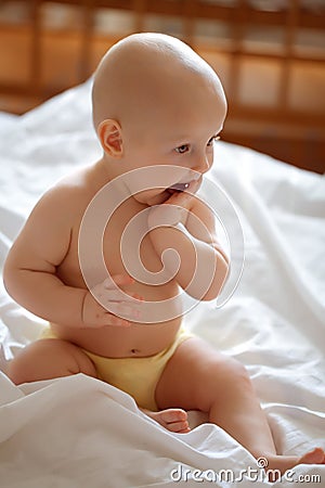 Cute little girl sitting on the bed Stock Photo