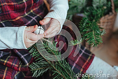 Cute little girl is sitting by the Christmas tree on the floor in the room. Near the baby is a gingerbread house and a basket with Stock Photo