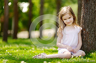 Cute little girl sitting on a clover field Stock Photo