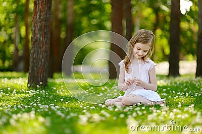 Cute little girl sitting on a clover field Stock Photo