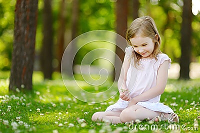 Cute little girl sitting on a clover field Stock Photo