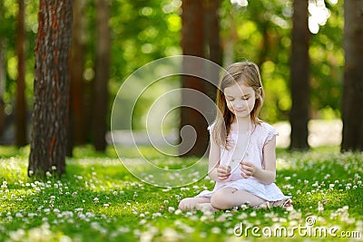 Cute little girl sitting on a clover field Stock Photo