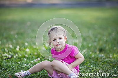 Cute little girl sitting on a clover field Stock Photo