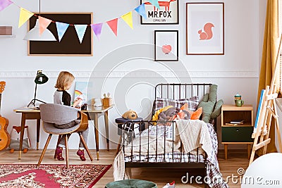 Cute little girl sitting at desk in her stylish vintage bedroom with workspace Stock Photo