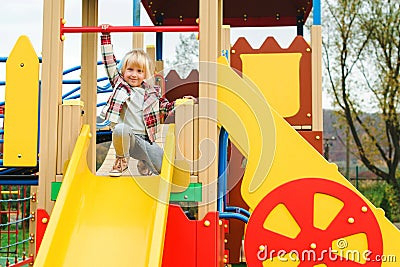 Cute little girl on a slide, outdoors. Adorable funny girl at modern colorful playground. Happy and healthy childhood. Active Stock Photo