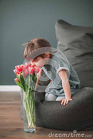 Cute little girl sniffing pink tulips Stock Photo
