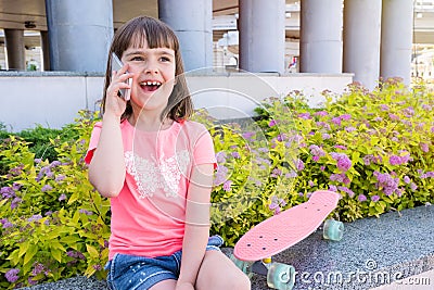 The cute little girl speaks by phone in the city. Emotional child Stock Photo