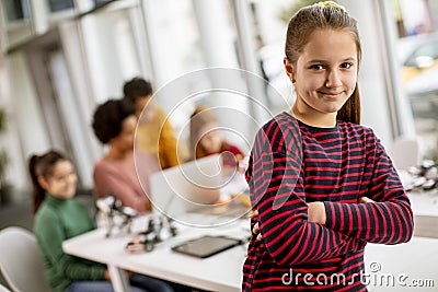 Cute little girl standing in front of kids programming electric toys and robots at robotics classroom Stock Photo