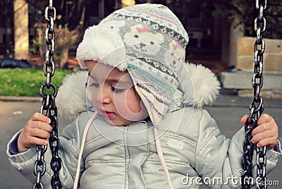 Cute little girl on the swing in winter; retro Instagram style Stock Photo