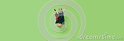 Cute little girl, talanted musician wearing huge mother& x27;s heels shoes jumping with violin, having fun isolated over Stock Photo