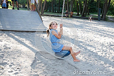 Little girl toddler having fun on the playground zip line in city park Stock Photo