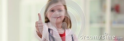 Cute little girl in uniform of medic shows thumb up gesture Stock Photo
