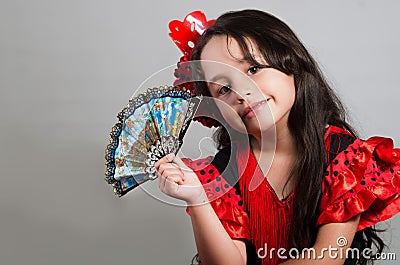Cute little girl wearing beautiful red and black dress with matching head band, posing for camera using chinese hand fan Stock Photo