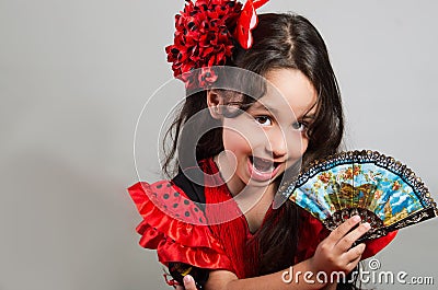 Cute little girl wearing beautiful red and black dress with matching head band, posing for camera using chinese hand fan Stock Photo