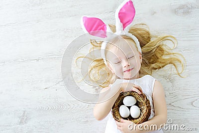 Cute little girl wearing bunny ears playing egg hunt on Easter Stock Photo