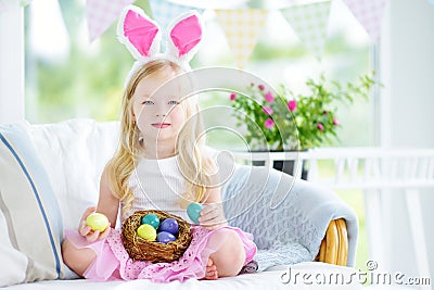 Cute little girl wearing bunny ears playing egg hunt on Easter Stock Photo