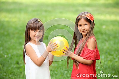 Cute little girls with ball in park on summer day Stock Photo