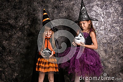 Cute little girls dressed as witches for Halloween near dark wall Stock Photo