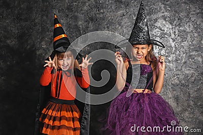 Cute little girls dressed as witches for Halloween near dark wall Stock Photo