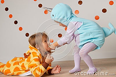 Cute little girls in giraffe and narwhal costume play at home. Halloween party Stock Photo