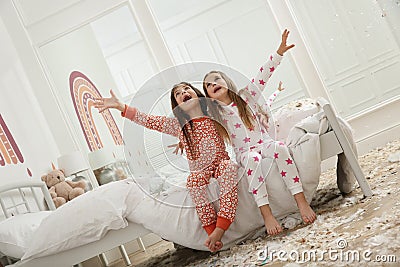 Cute little girls sitting on bed in room after pillow fight. Happy childhood Stock Photo