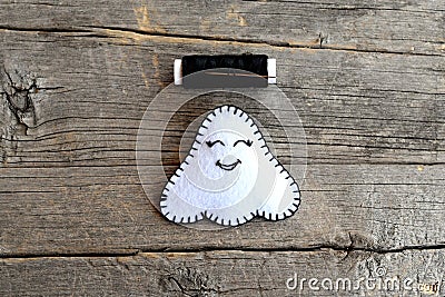 Cute little Halloween ghost ornament and black thread isolated on old wooden background. Hand toy is made of white felt. Step Stock Photo