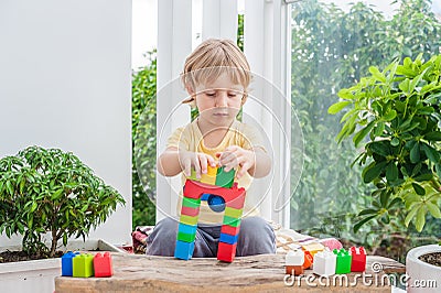 Cute little kid boy with playing with lots of colorful plastic blocks indoor. Active child having fun with building and creating o Stock Photo