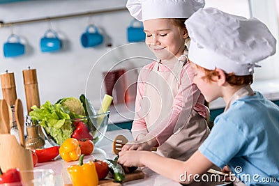 cute little kids in chef hats preparing vegetable salad together Stock Photo