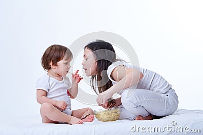Cute little playful sisters eating yummy pasta in white studio background Stock Photo