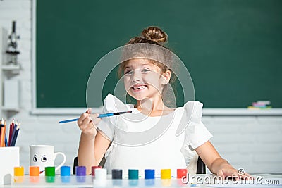 Cute little preschooler child girl drawing at school. Child girl painting on elementary school. Funny kids emotions. Stock Photo