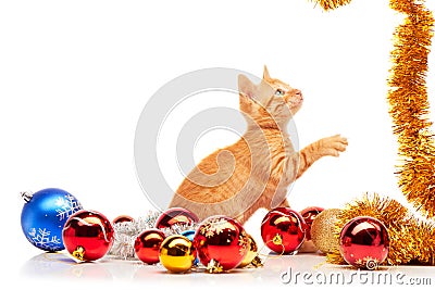 Cute little red kitten playing with golden tinsel near colorful and sparkly Christmas toys Stock Photo