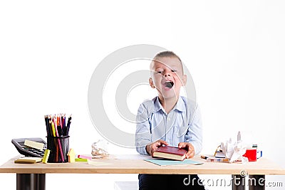 Cute little school boy with huge smile sitting at his desk on white background. Happy intelligent children in shirt with blue eye Stock Photo