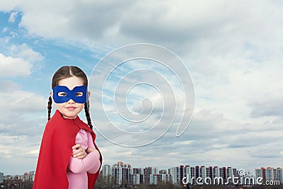 Cute little super hero girl in the red cloak against the urban background Stock Photo