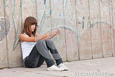 Cute lonely teenage girl sitting in urban environm Stock Photo