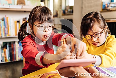 Cute lovely sisters with chromosome abnormality drawing with crayons Stock Photo