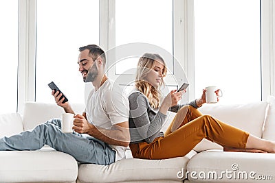Cute loving couple indoors at home using mobile phones Stock Photo