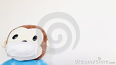 Cute monkey soft toy wearing a face mask with pale white background. Stock Photo