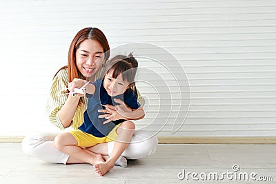 Cute mother and daughter Hugging and teasing each other sitting on the floor of the house. Stock Photo