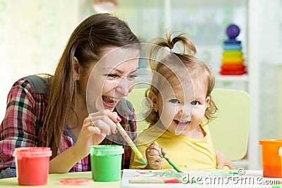 Cute mother teach her daughter kid to paint Stock Photo