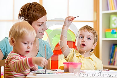 Cute mother teaching her kids to paint Stock Photo