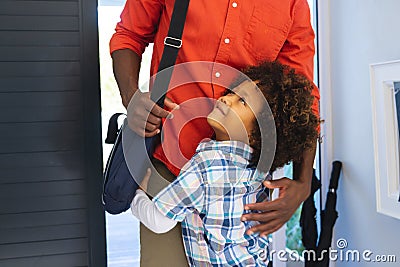 Cute multiracial boy with afro hair cuddling young father arrived from work at home Stock Photo