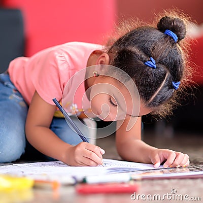 Cute multiracial small girl drawing on a coloring book Stock Photo