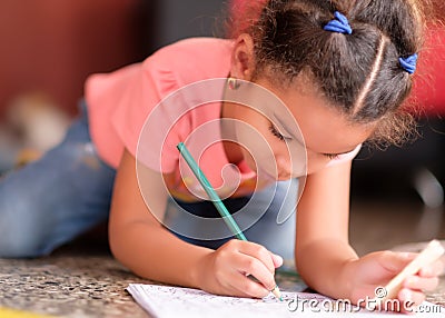 Cute multiracial small girl drawing on a coloring book Stock Photo